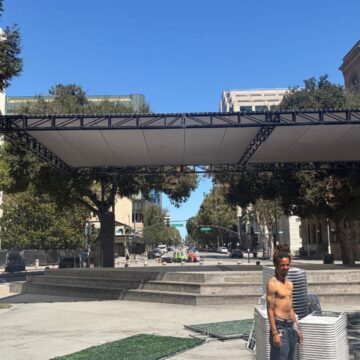 Two men standing in a plaza with stacks of plastic chairs in San Jose, California