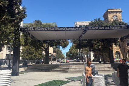 Two men standing in a plaza with stacks of plastic chairs in San Jose, California