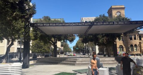 Two men standing in a plaza with stacks of plastic chairs in San Jose, California