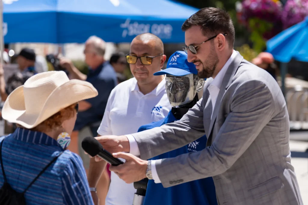 A person holding a microphone for another person to ask a robot a question in Mountain View, California