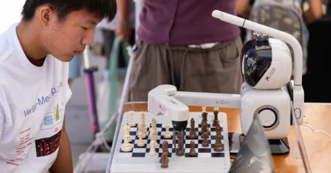 A high school student playing chess with a robot at a tech showcase in Mountain View, California