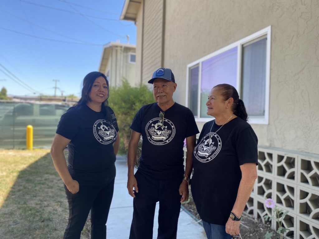 Three people standing in front of an apartment complex in San Jose, California