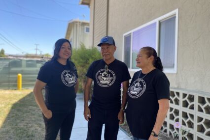 Three people standing in front of an apartment complex in San Jose, California