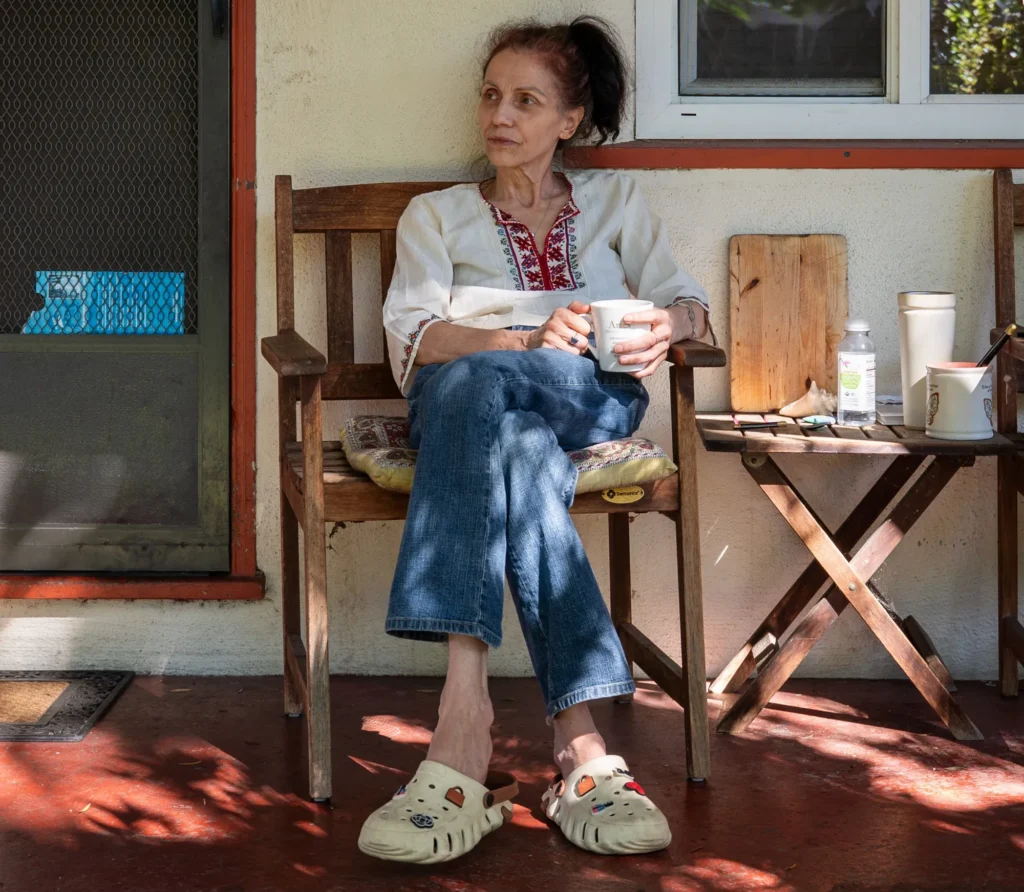 A woman sitting in a chair holding a mug outside her apartment in Mountain View, California