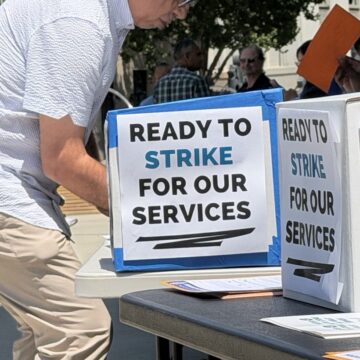 A man votes behind a cardboard barrier.