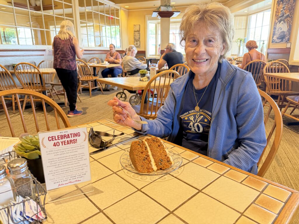 A woman sitting at a table with a slice of cake