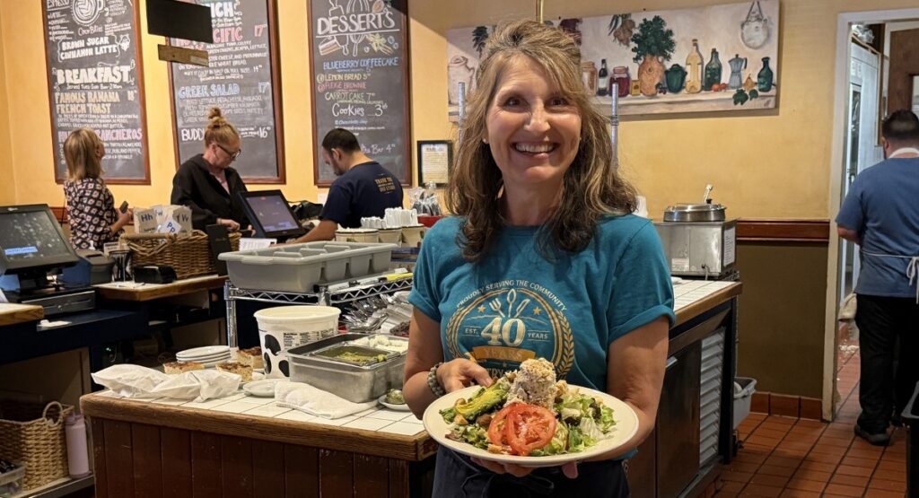 A woman standing in a restaurant with a plate of food in Sunnyvale, California