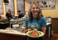 A woman standing in a restaurant with a plate of food in Sunnyvale, California