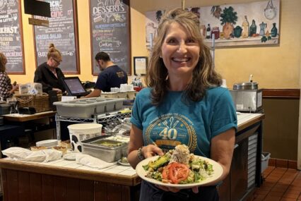 A woman standing in a restaurant with a plate of food in Sunnyvale, California