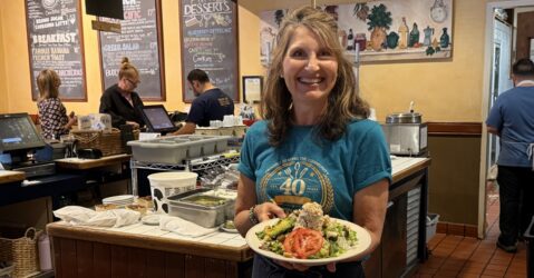 A woman standing in a restaurant with a plate of food in Sunnyvale, California