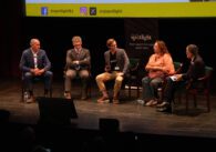 Five people sitting in chairs on a stage
