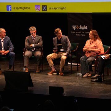 Five people sitting in chairs on a stage