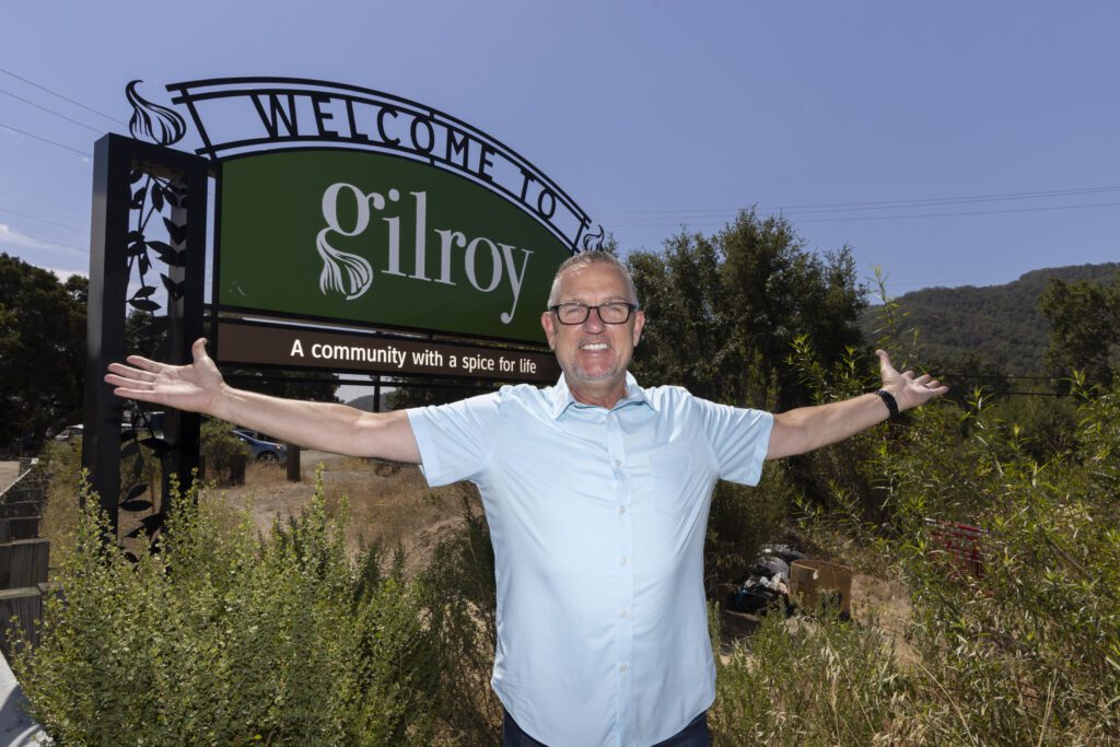 A man in glasses standing in front of a sign in Gilroy, California
