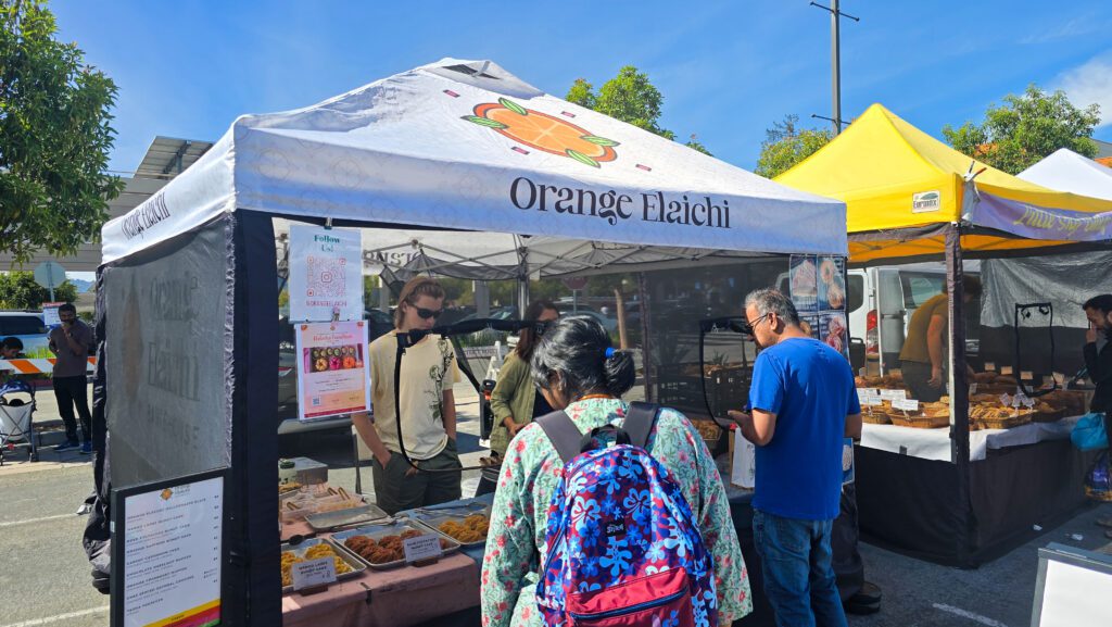 People getting food from a pop-up stand at a farmers market in Cupertino, California