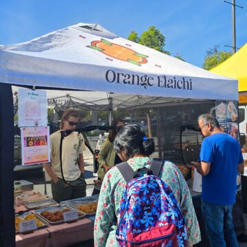 People getting food from a pop-up stand at a farmers market in Cupertino, California