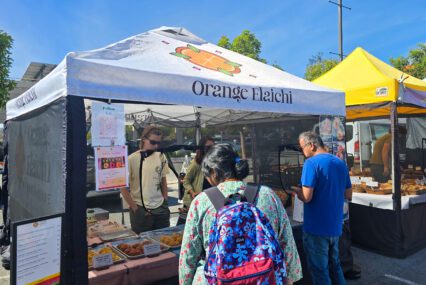 People getting food from a pop-up stand at a farmers market in Cupertino, California