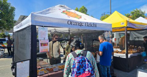 People getting food from a pop-up stand at a farmers market in Cupertino, California