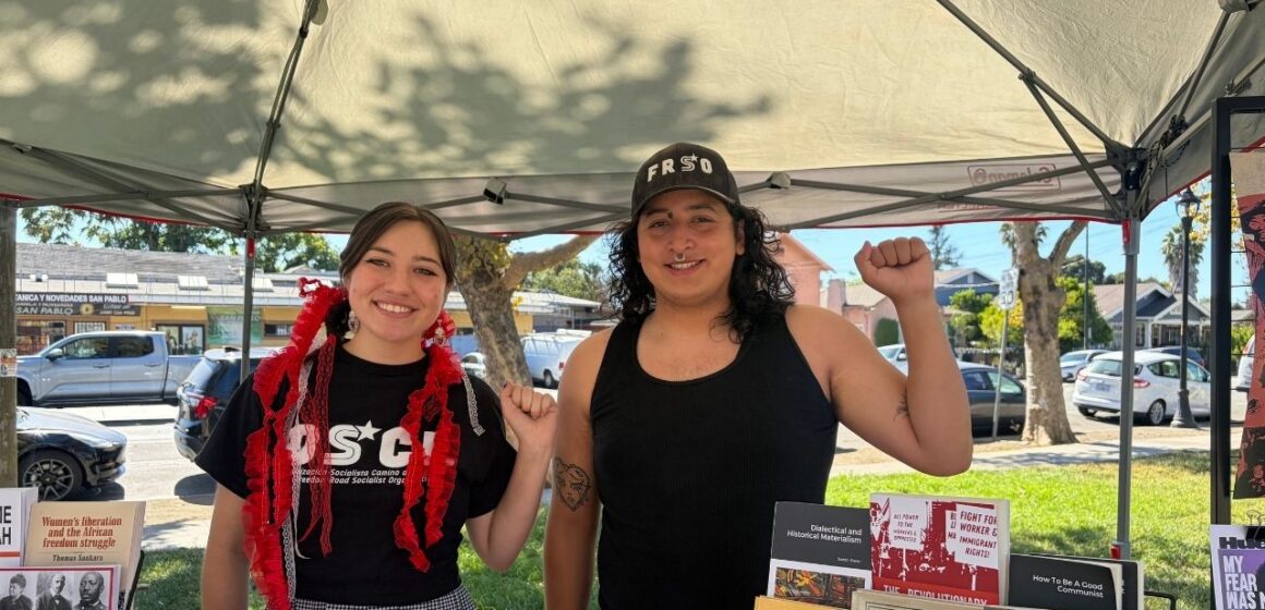 A man and woman standing under a canopy with their fists raised in the air in San Jose, California