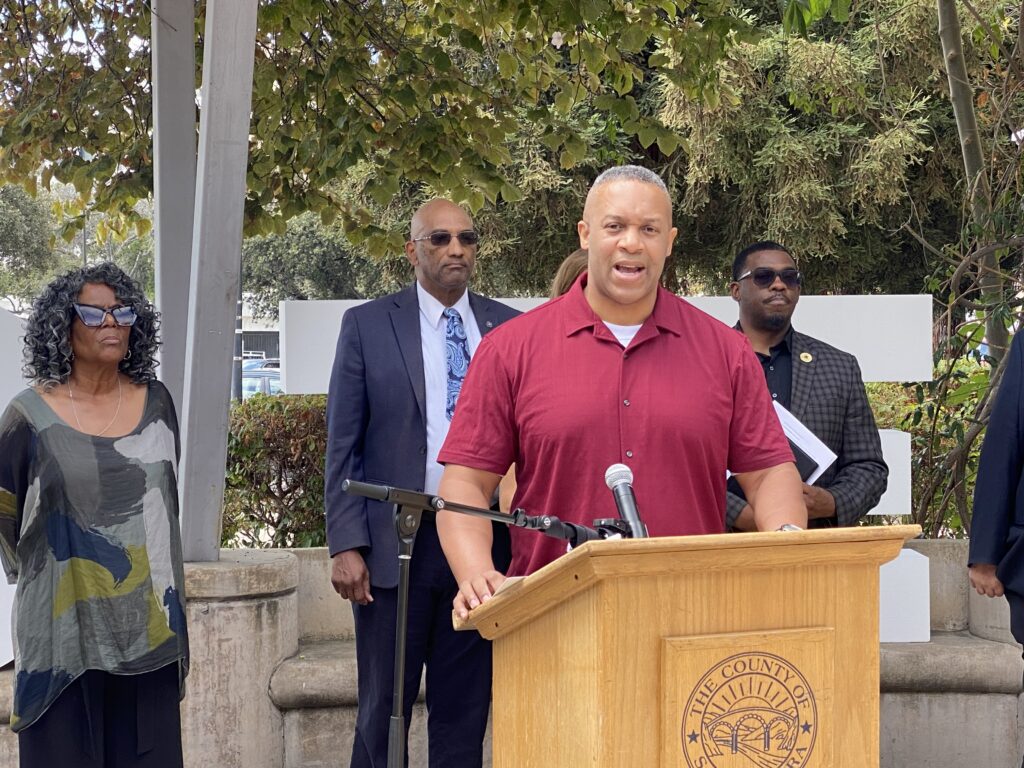 A man standing at a podium with other people behind him in San Jose, California