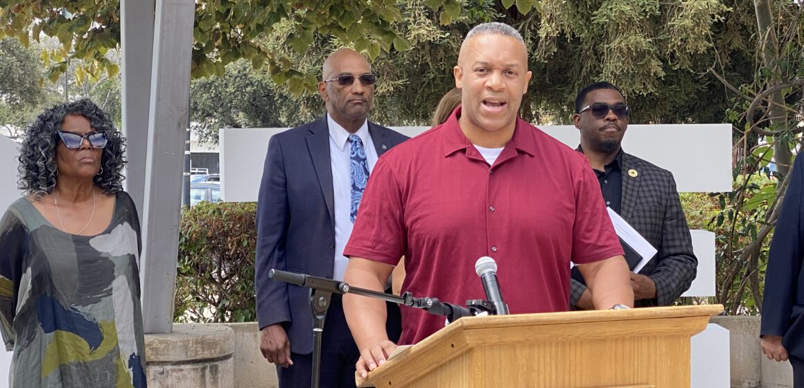 A man standing at a podium with other people behind him in San Jose, California
