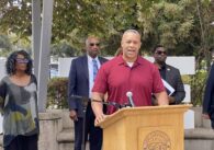 A man standing at a podium with other people behind him in San Jose, California