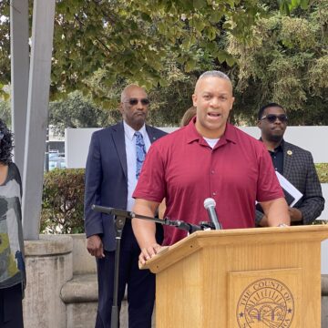 A man standing at a podium with other people behind him in San Jose, California