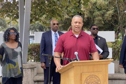 A man standing at a podium with other people behind him in San Jose, California