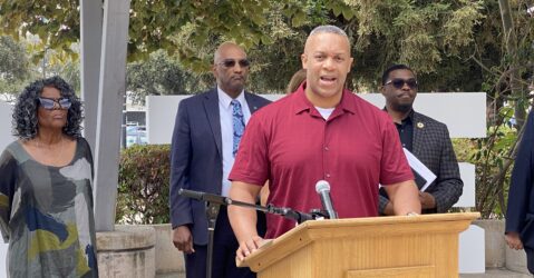 A man standing at a podium with other people behind him in San Jose, California