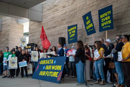 A group of people with signs rallying in front of city hall in San Jose, California
