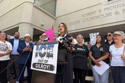 A woman speaking at a podium outside a courthouse in San Jose, California