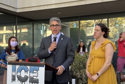 A man speaking into a microphone at a podium outside in San Jose, California