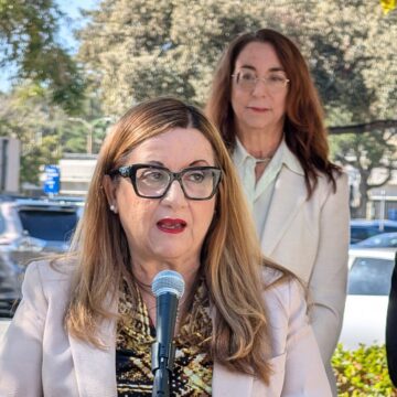 Una mujer hablando por un micrófono, con otras mujeres de pie detrás de ella en San José, California.