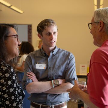 Tres personas conversando en una jornada de puertas abiertas en San José, California.