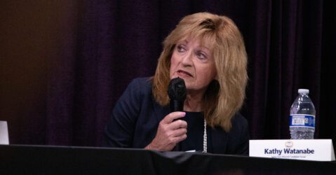 A woman holding a microphone at an election forum in Santa Clara, California