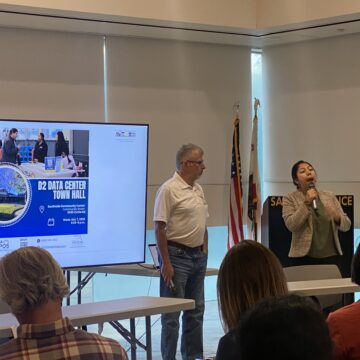 People conducting a presentation in front of a projector screen