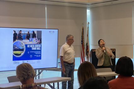 People conducting a presentation in front of a projector screen