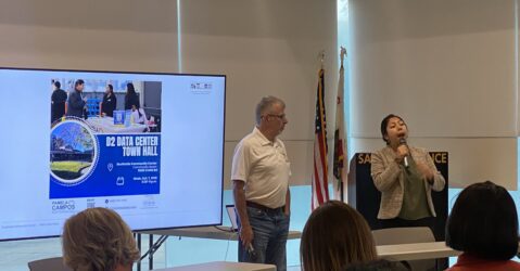 People conducting a presentation in front of a projector screen