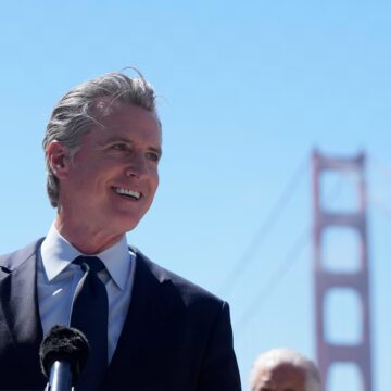 California Gov. Gavin Newsom The governor of California standing in at a microphone, with the Golden Gate Bridge in the background
