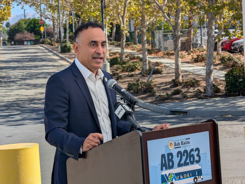 A man speaks into a microphone at a podium outside in San Jose, California