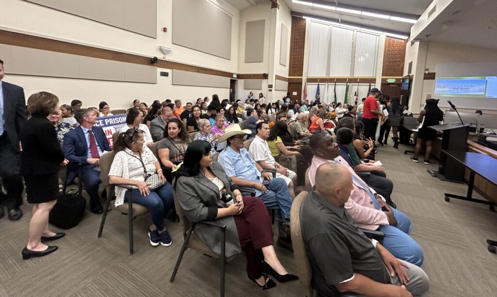 crowd of people sitting down in a room looking forward.