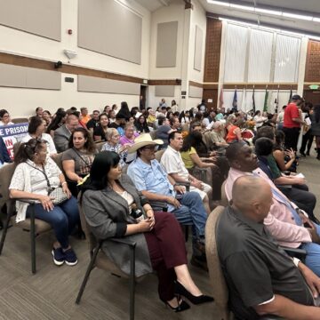 Gilroy City Council meeting attendees crowd of people sitting down in a room looking forward.