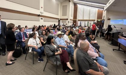 Gilroy City Council meeting attendees crowd of people sitting down in a room looking forward.