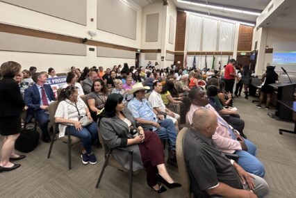 crowd of people sitting down in a room looking forward.