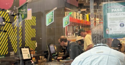 Shoppers scan goods in a self-checkout line.
