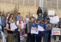 A group of people holding protest signs outside city hall in San Jose, California