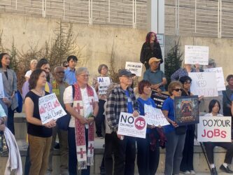A group of people holding protest signs outside city hall in San Jose, California