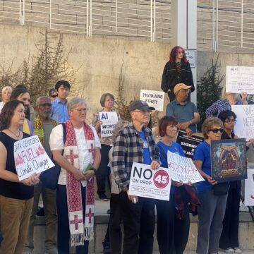 A group of people holding protest signs outside city hall in San Jose, California
