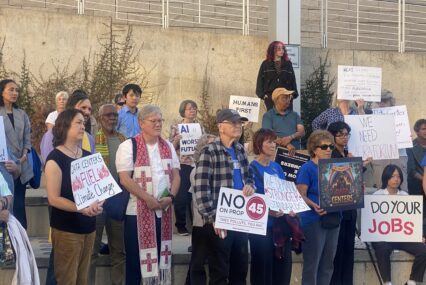 A group of people holding protest signs outside city hall in San Jose, California
