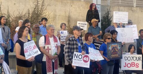 A group of people holding protest signs outside city hall in San Jose, California