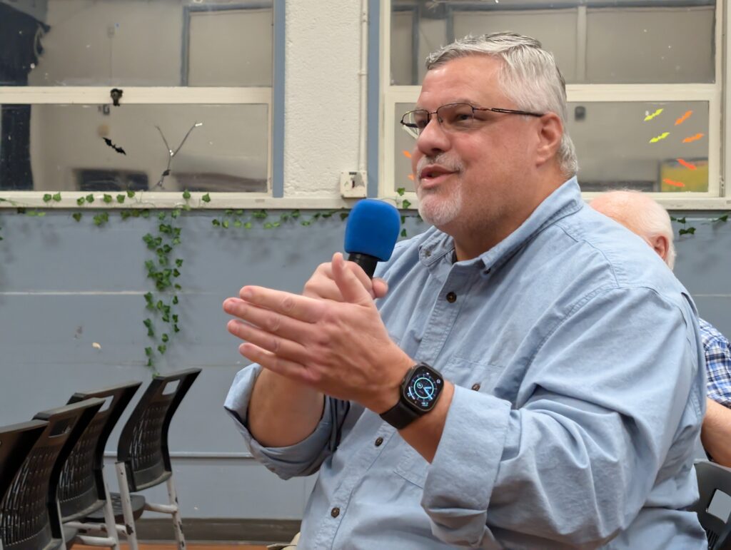 A man in a blue collar shirt holding a microphone